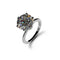 A round brilliant-cut gemstone solitaire ring in a polished silver-tone setting, shown on a clean white background with a soft shadow.
